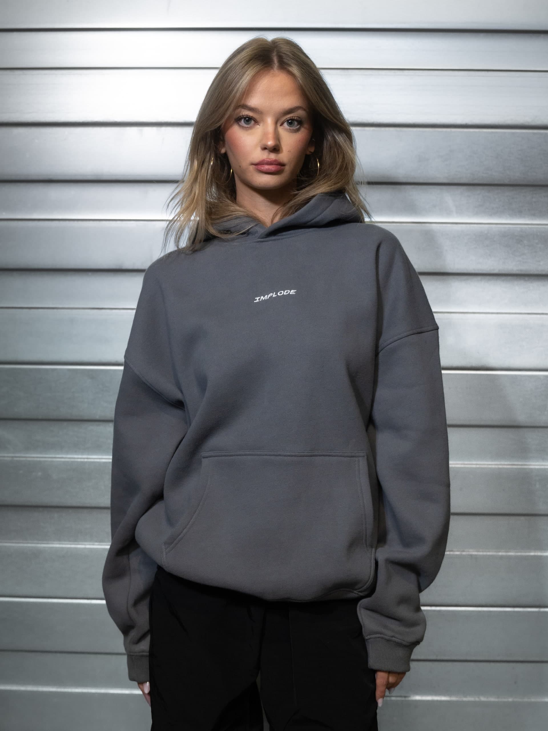 Frau im grauen Sweatshirt vor einer Metallwand