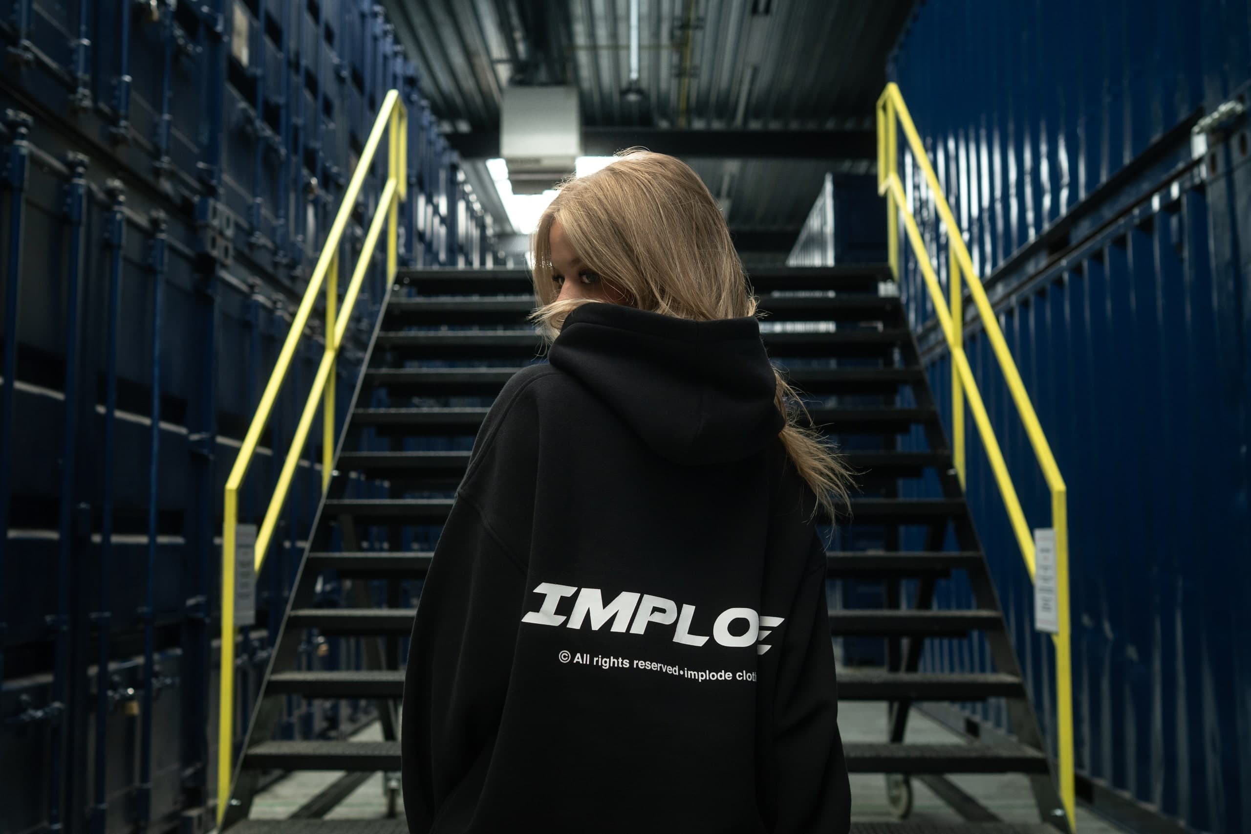 Rückansicht einer Person im schwarzen Hoodie auf einer Treppe