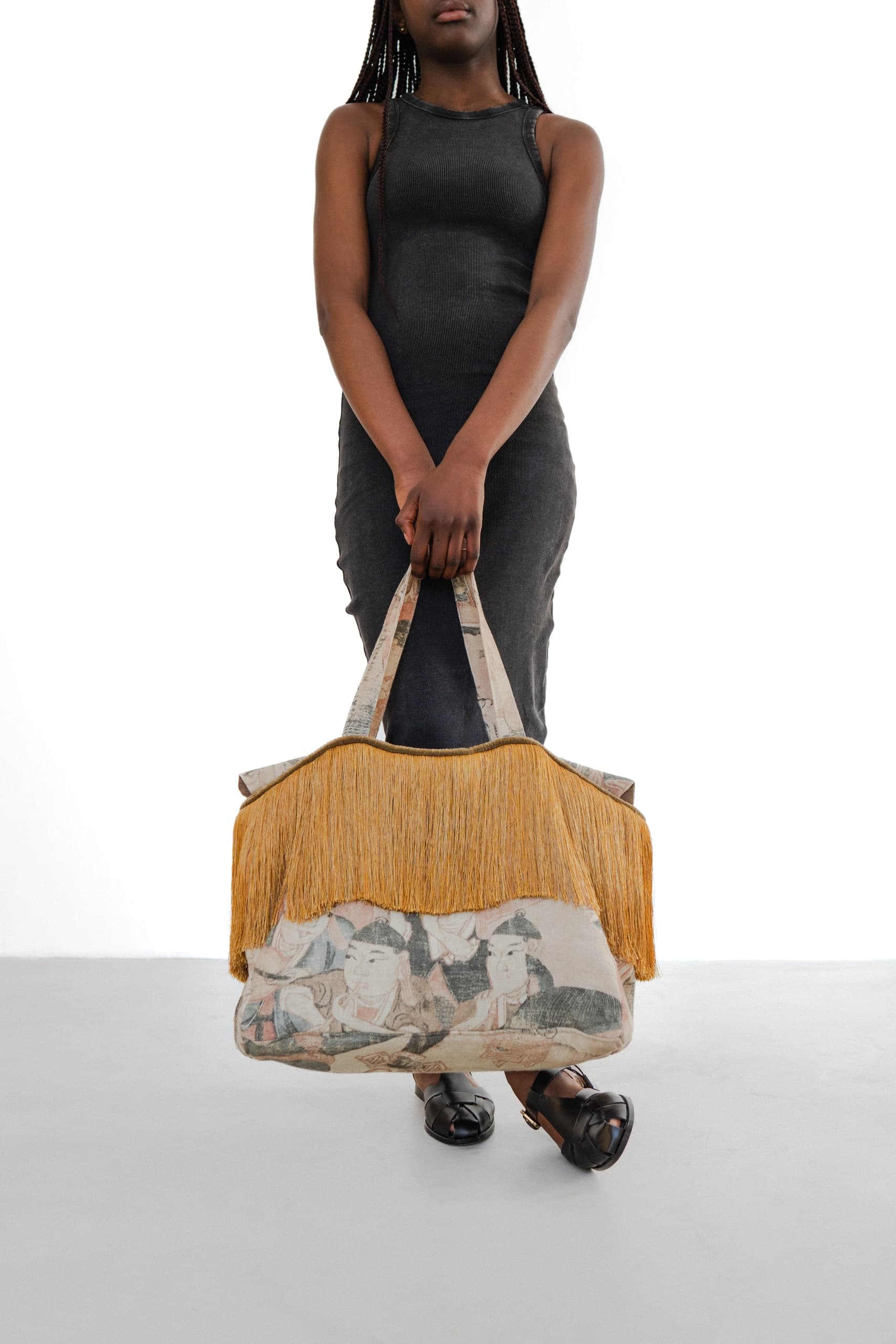 Model im schwarzen Kleid mit einer mehrfarbigen Tasche
