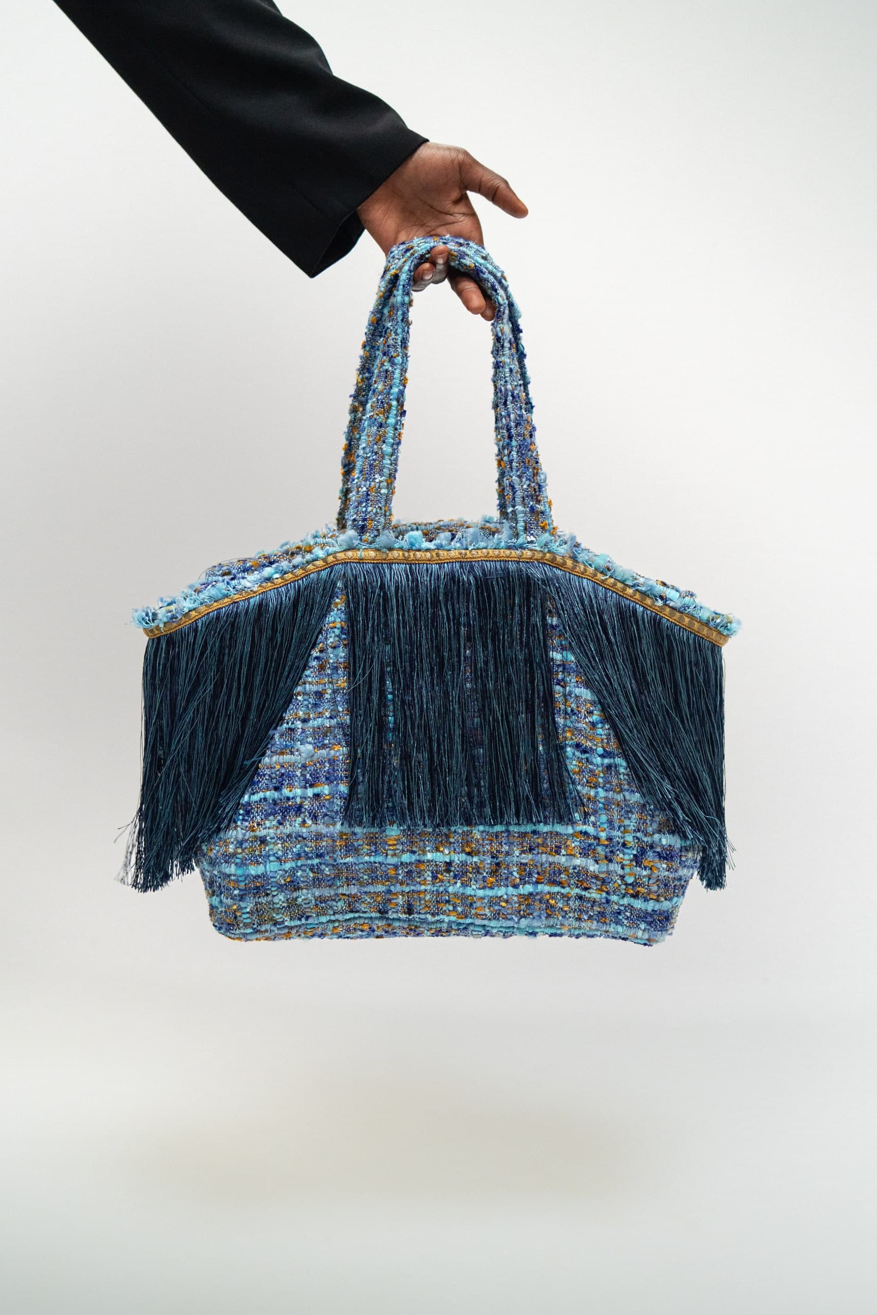 Hand mit einer blauen Tasche vor weißem Hintergrund