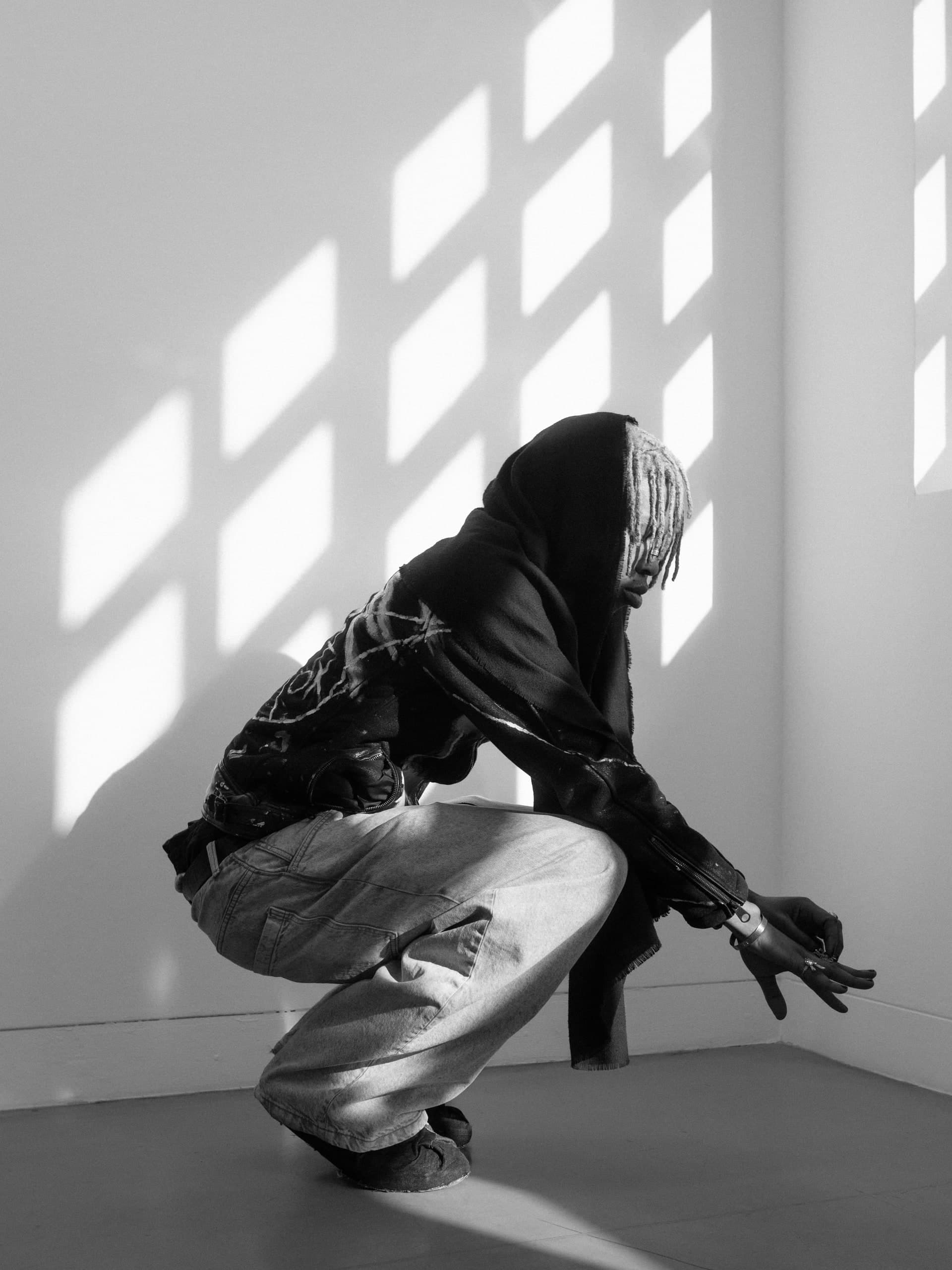 Person in der Hocke unter geometrischen Fensterschatten