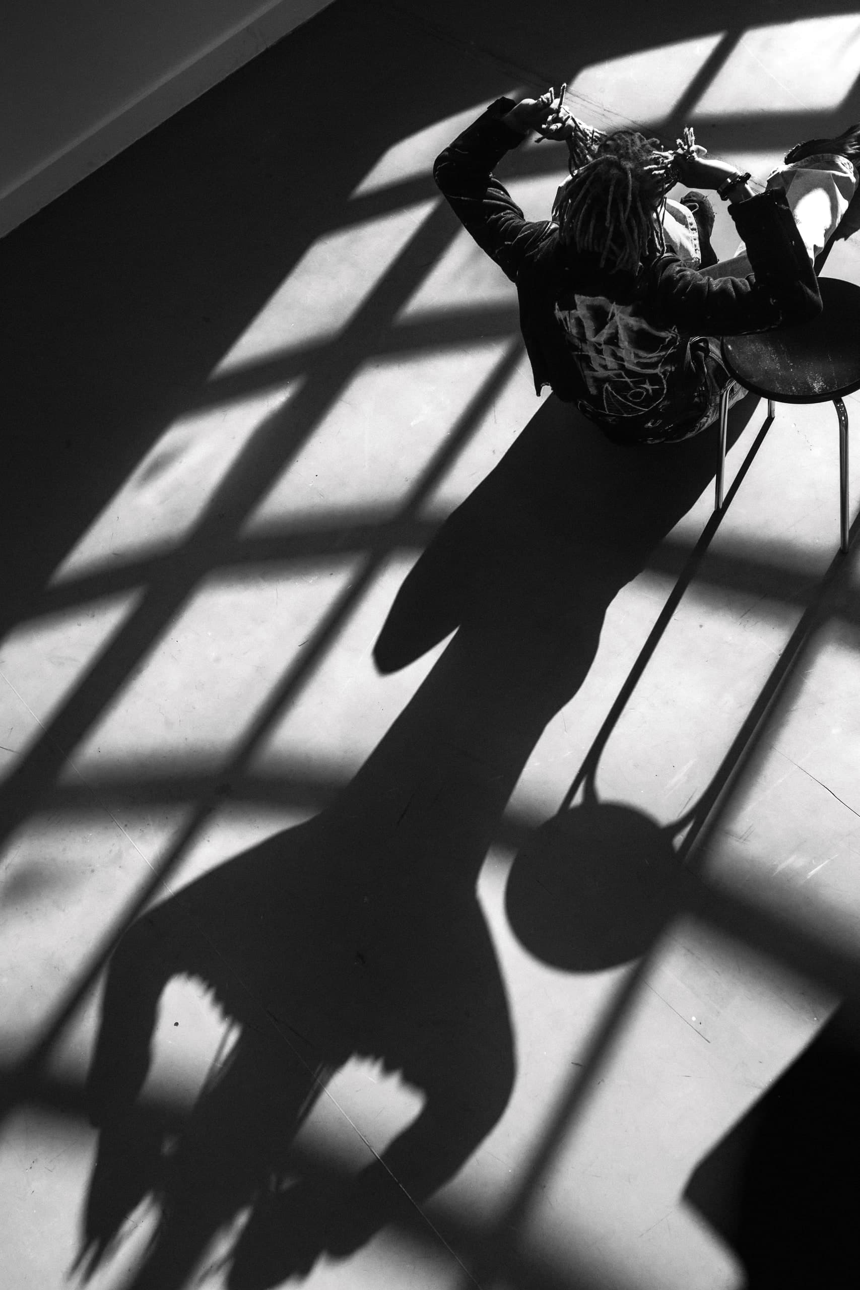 Person am Boden in einem Raster aus Licht und Schatten
